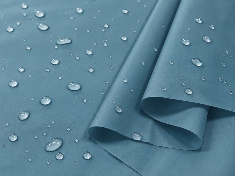 Water droplets beading on the surface of water-repellent nylon taffeta fabric.